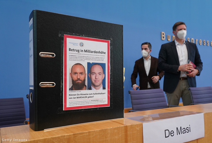 Fabio de Masi és Florian Toncar, a Bundestag Wirecard-botrányt vizsgáló bizottságának tagjai sajtótájékoztatóra készülnek, miközben Jan Marsalek volt Wirecard-vezérigazgató rendőrségi körözési plakátja látható egy mappán 2021. március 10-én Berlinben