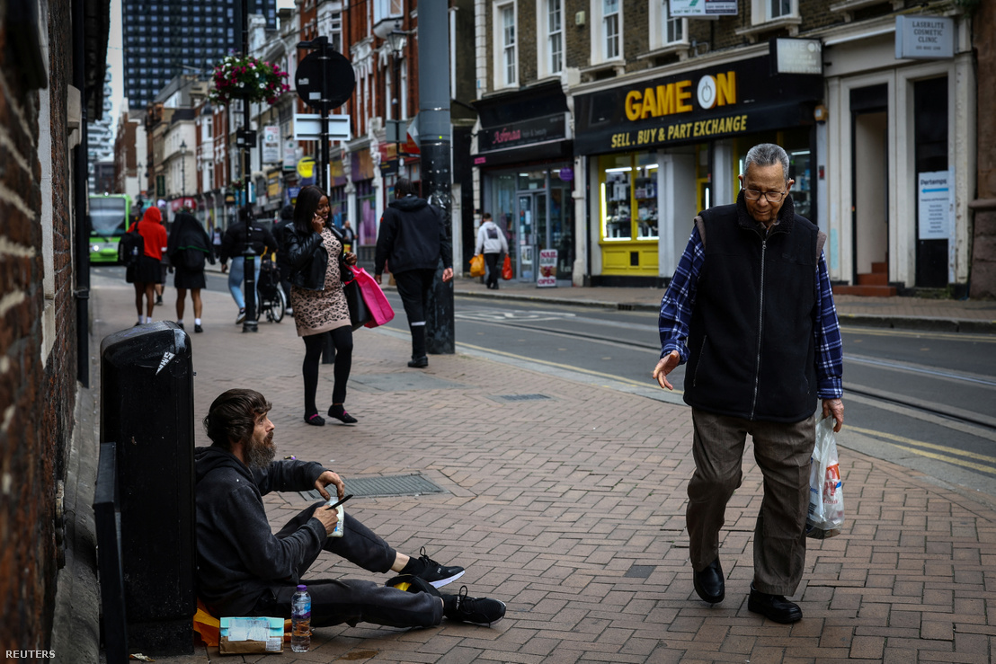 Emberek sétálnak el egy hajléktalan férfi mellett a dél-londoni Croydon egyik főutcáján Nagy-Britanniában 2024. június 13-án