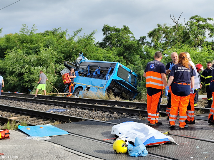 Mentőszemélyzet dolgozik egy autóbusszal ütköző vonat balesetének helyszínén Érsekújvár közelében 2024. június 27-én