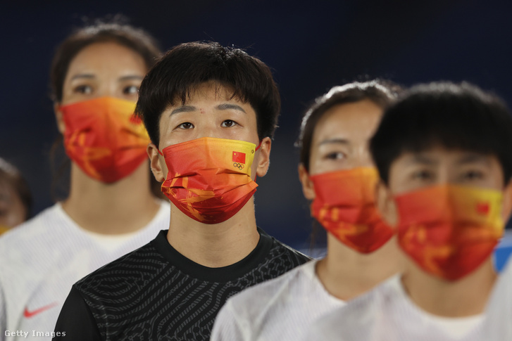 A kínai csapat arcmaszkot visel a mérkőzés előtt Tokióban