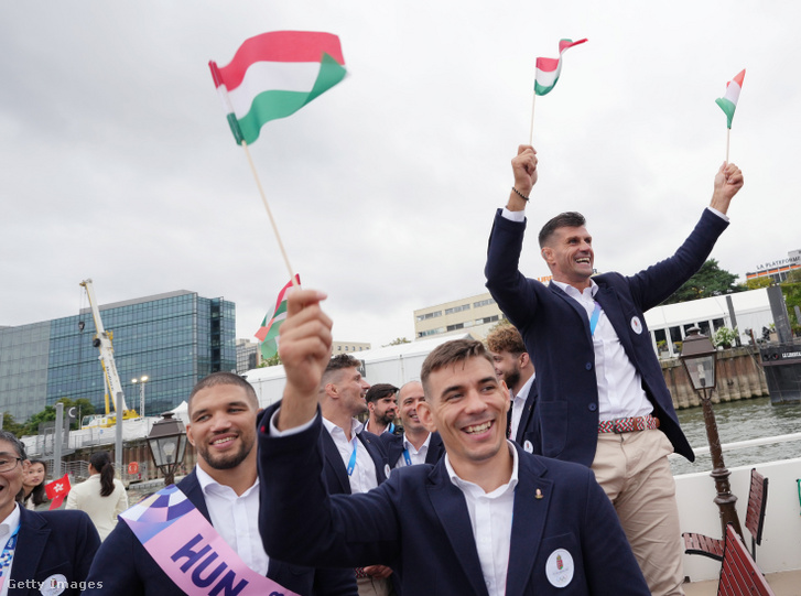 A magyar olimpiai csapat tagjai nemzeti színű zászlókkal kezükben egy hajón a Szajna folyón a 2024-es párizsi nyári olimpia megnyitóünnepségén 2024. július 26-án
