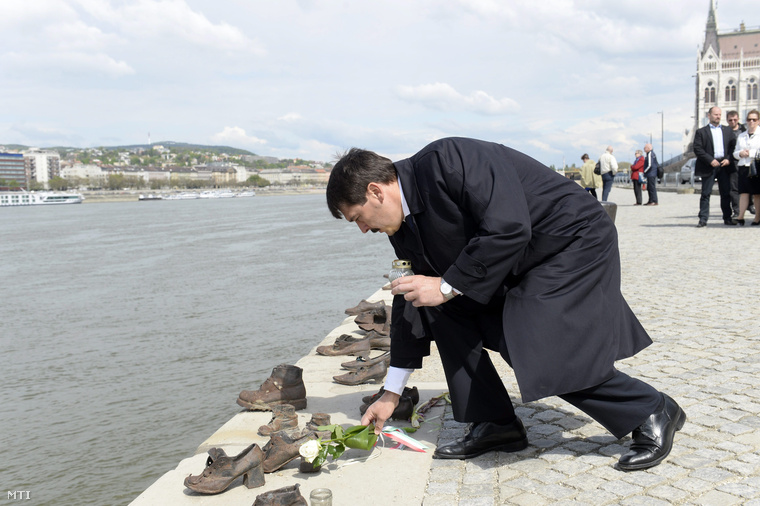 Áder János köztársasági elnök virágot és mécsest helyez el a Cipők a Duna-parton emlékműnél