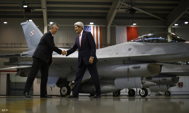 John Kerry és a lengyel védelmi miniszter kezet fognak egy lengyelországi hangárban (2012.)