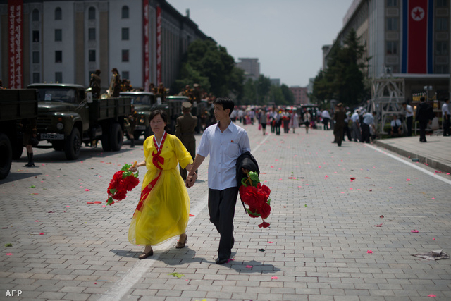 Egy pár sétál kézen fogva egy phenjani katonai parádén.