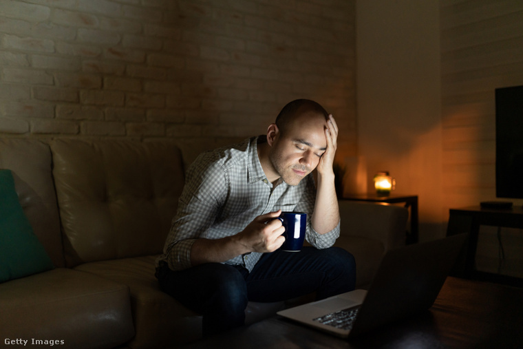 Egy férfi este iszik kávét a laptopja előtt. (Fotó: Antonio_Diaz / Getty Images Hungary)