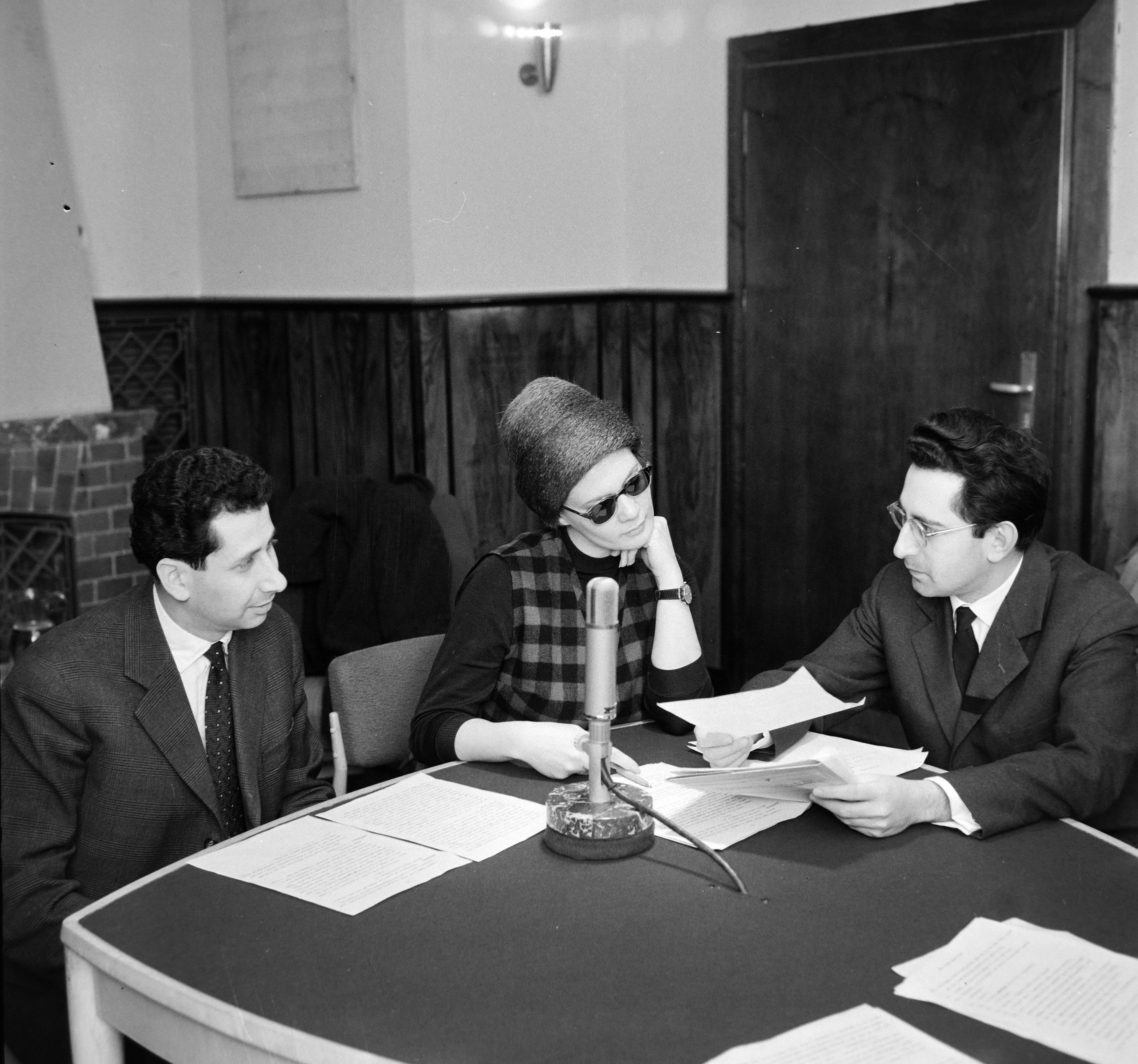 A Magyar Rádió 19-es stúdiója, az Új Zenei Újság című műsor. Kroó György zenetörténész, kritikus, Bara Margit színművésznő, Sebestyén János orgona- és csembalóművész, rádiós személyiség.
