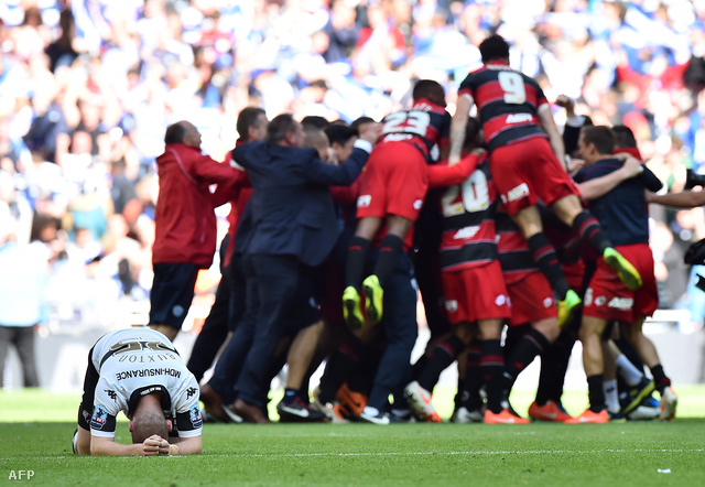 Jake Buxton a Derby County védője búslakodik miközben a háttérben a QPR játékosai ünnepelnek.