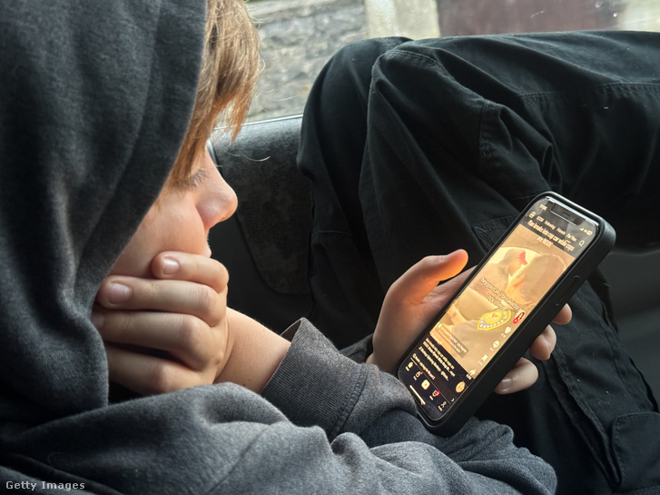 Egy fiú a telefon képernyőjét nézi 2024. október 20-án