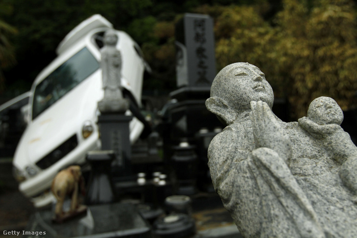 Egy autó és buddhista szobrok, amelyeket a 2011. március 11-én Japán északkeleti részén bekövetkezett földrengés és cunami pusztított el