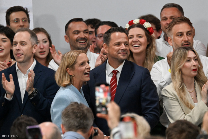 Rafal Trzaskowski, a Polgári Koalíció elnökjelöltje, Varsó polgármestere és felesége, Malgorzata Trzaskowska áll, miközben támogatói az elnökválasztás második fordulójának exit polljaira reagálnak a lengyelországi Varsóban 2025. június 1-jén