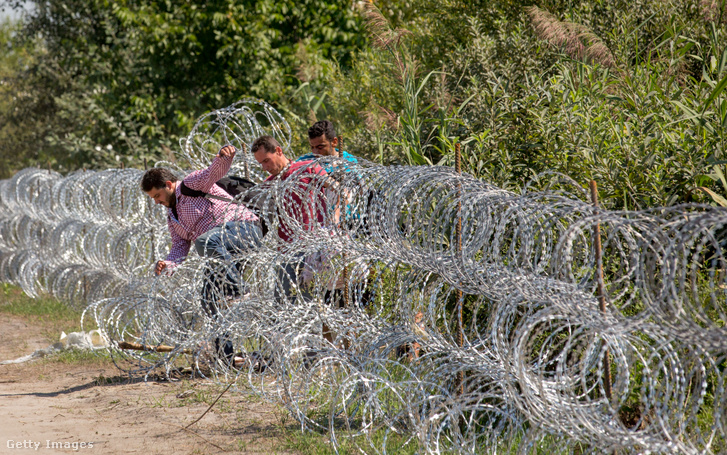 Migránsok ugranak át a Szerbia és Magyarország közötti határkerítésen 2015. augusztus 30-án