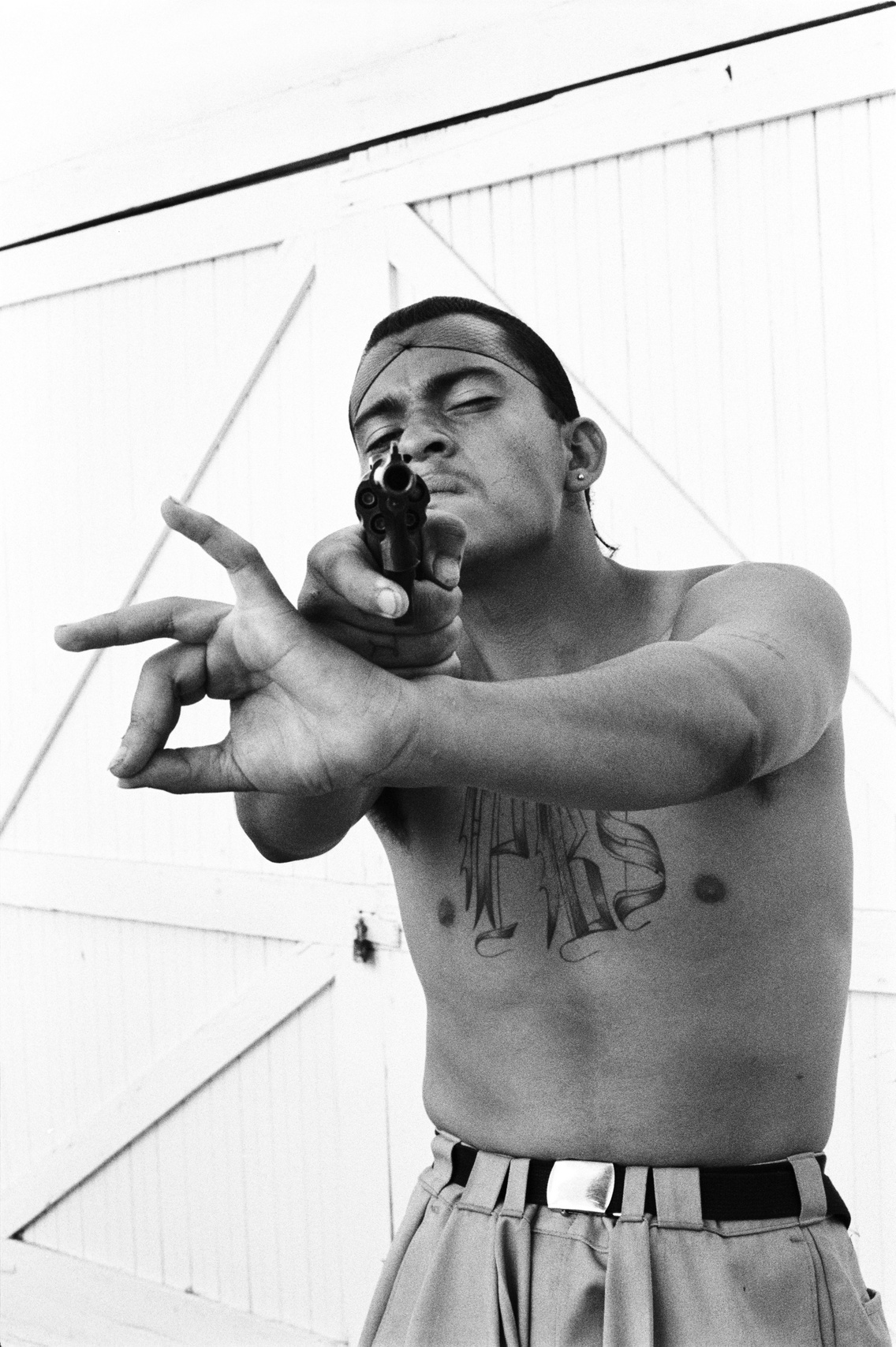 Muerto, a Playboys gang tagja a banda kézjelét mutatja, és egy üreges hegyű lövedékkel töltött revolvert villant, 1992