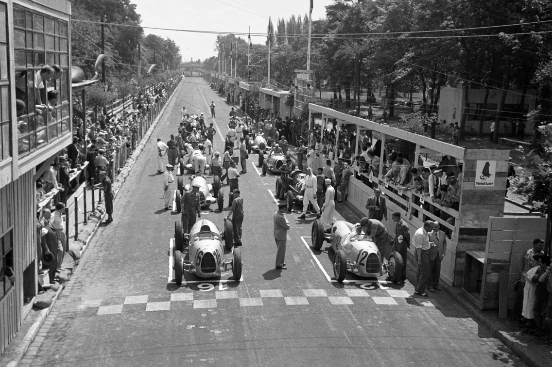 A felvétel az első ízben megrendezésre kerülő Magyar Automobil Grand Prix alkalmával készült. A rajtrácson az Auto Union versenyautói, első helyről 16-os számmal Breuid Rosemeyer, a második pozícióból 12-es számmal Hans Stuck rajtol, Népliget, 1936