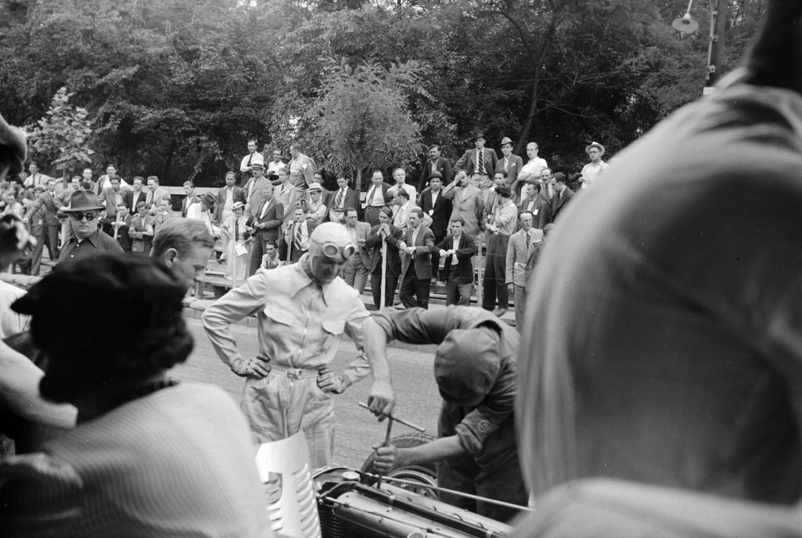 A felvétel az első ízben megrendezésre kerülő Magyar Automobil Grand Prix alkalmával készült. A Mercedes-Benz autóversenyzője, Louis Chiron nézi a Mercedes-Benz W25E típusú versenyautójának javítását, Népliget, 1936