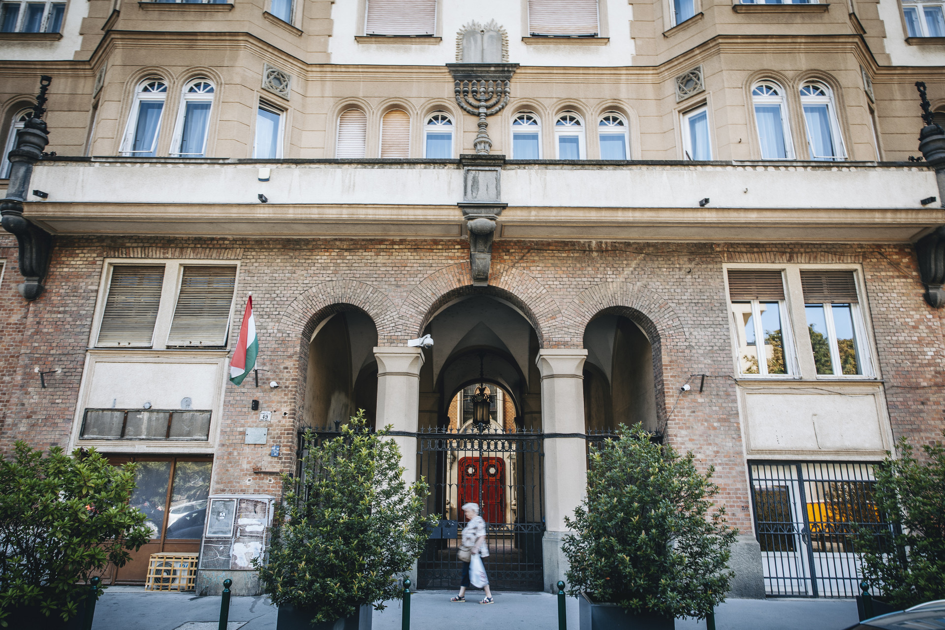 Épp csak felsejlik a zsinagóga, amire az épületdíszek közül a menóra és a kőtáblák is utalnak