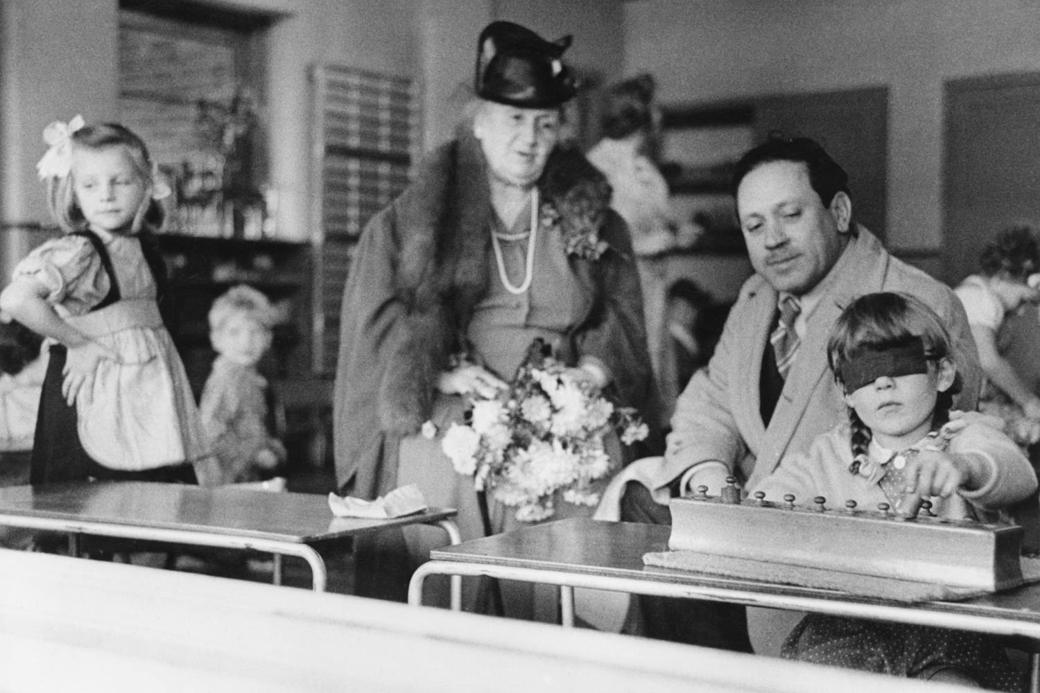 Az olasz pedagógus és a Montessori-iskolák alapítója, Maria Montessori. A kép 1946-ban készült egy londoni osztályteremben, ahol egy fiatal lány éppen koordinációs feladatot végez.