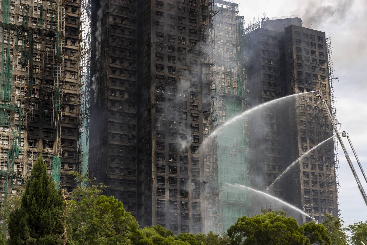A helyi tűzoltók megfeszített erővel dolgoznak 2025. november 27-én, Hongkongban, a Taj Po negyedben kigyulladt lakótömb oltásán.
