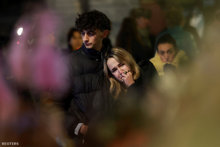 Gyászolók gyűlnek össze, hogy virágokat és gyertyákat helyezzenek el a Le Constellation bár előtt 2026. január 1-jén