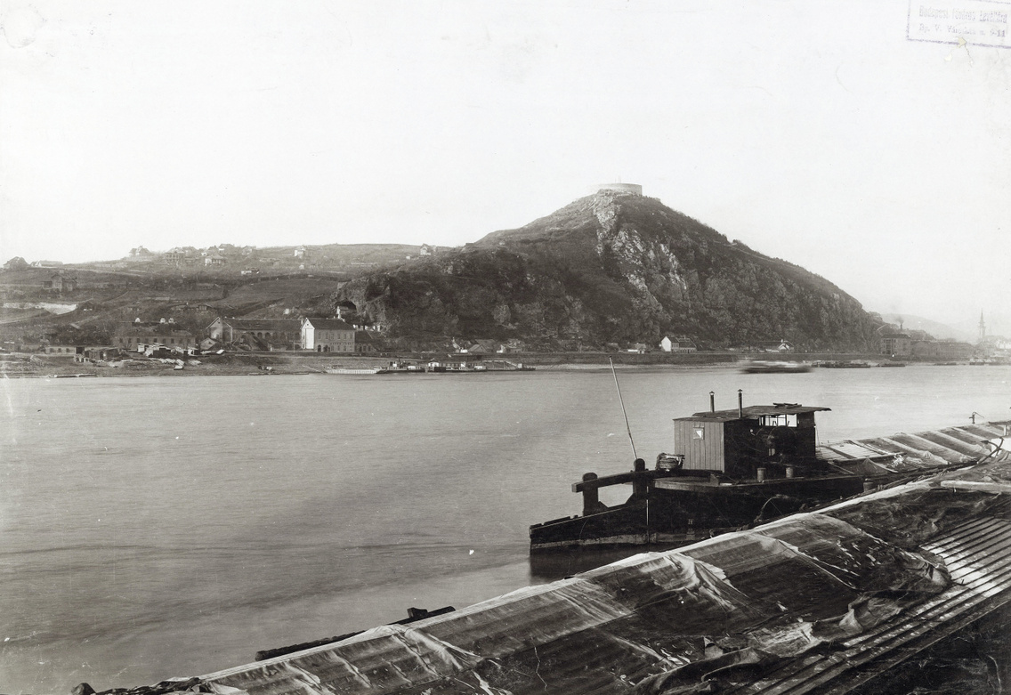 A Gellért-hegy a Fővámpalota előtti rakpartról nézve. Fenn a Citadella, a hegy lábánál a Sáros fürdő. A felvétel 1894-ben készült