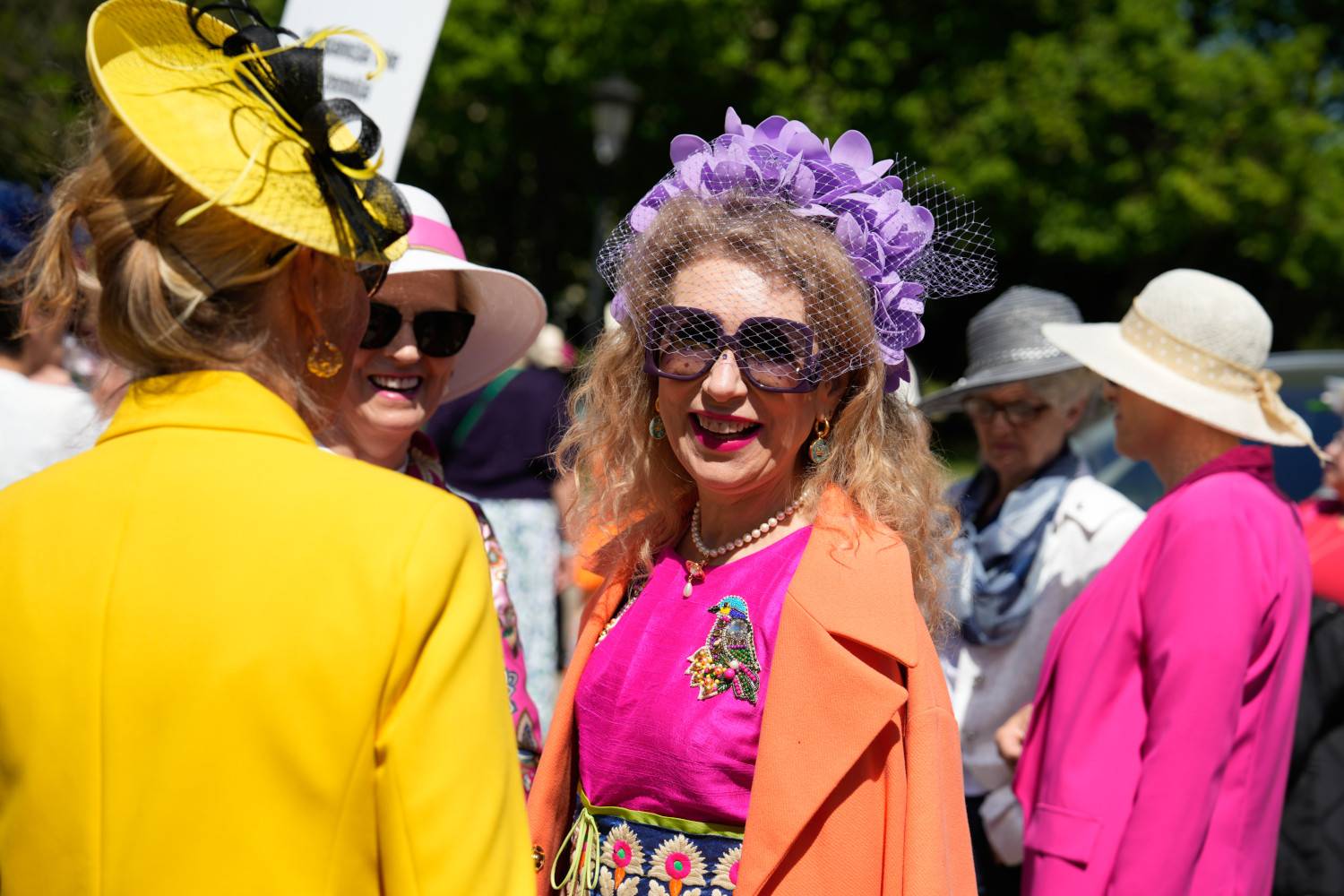 A sárga-fekete, extravagáns kalapból és a lila virágkoszorúból is csakúgy árad a felhőtlen magabiztosság és nőiesség.