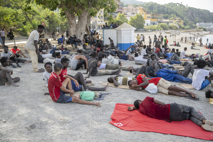 Migránsok gyülekeznek és pihennek a tengerparton a spanyol polgárőrség (Guardia Civil) felügyelete mellet 2026. augusztus 1-jén
