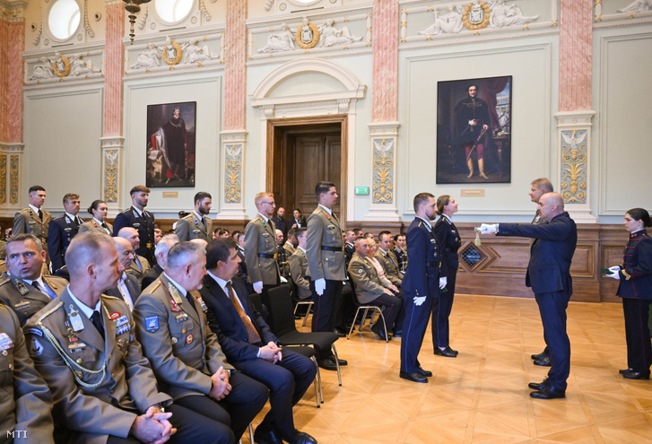 Baráth Ernő, a Honvédelmi Minisztérium humánstratégiáért felelős helyettes államtitkára (j2) és Kun Szabó István altábornagy, a Honvéd Vezérkar főnökének általános helyettese (j3) avatási szablyát és hadnagyi vállszalagot ad át az idén végzett honvéd tisztjelöltek kinevezési ünnepségén a Nemzeti Közszolgálati Egyetemen 2026. augusztus 18-án