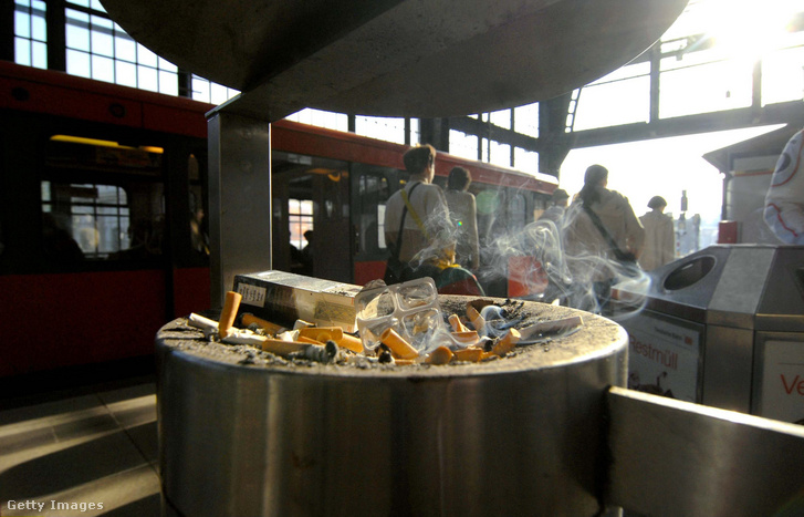 Füstölő cigarettacsikkek egy pályaudvarra kihelyezett hamutartóban
