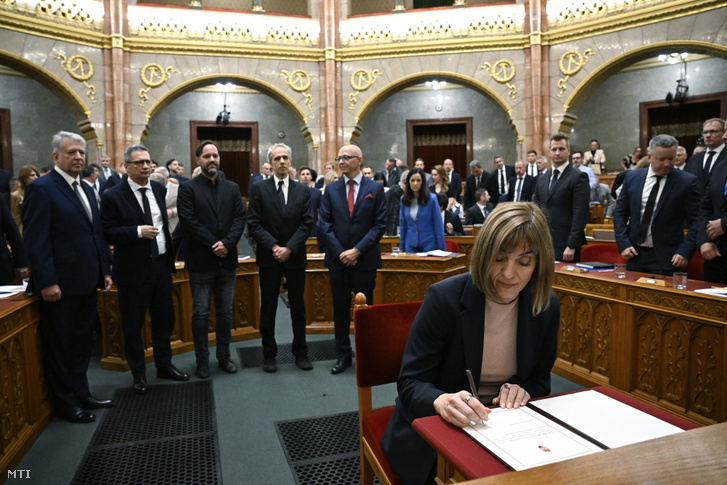Bayer Judit, a Független Közmédia Testület elnöke aláírja az eskü okmányait az Országgyűlés plenáris ülésén 2026. szeptember 8-án. Mögötte Szabó György, Sükösd Miklós, Kollár Árpád, Hargitai Miklós és Bálint Viktor, a Független Közmédia Testület tagjai (b-j)