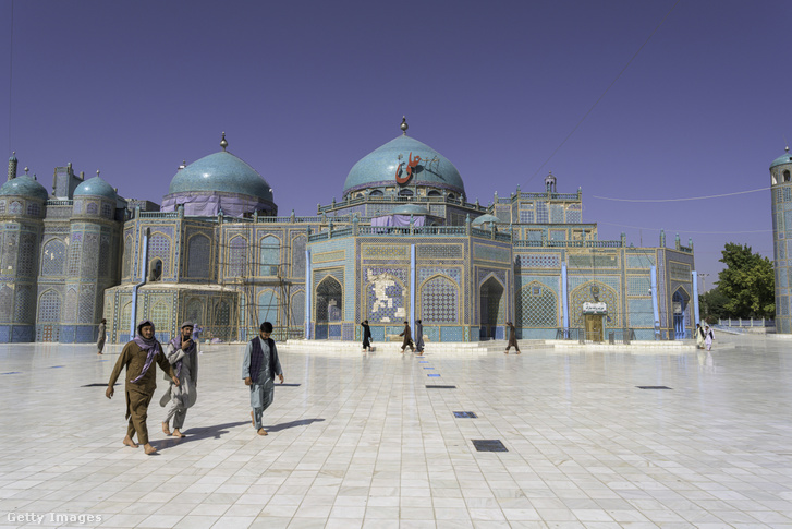 Emberek sétálnak egy kék csempékkel díszített szentély előtti hatalmas márványudvaron az afganisztáni Balkh tartományban található Mazar-i-Sharifban, 2026. május 7-én