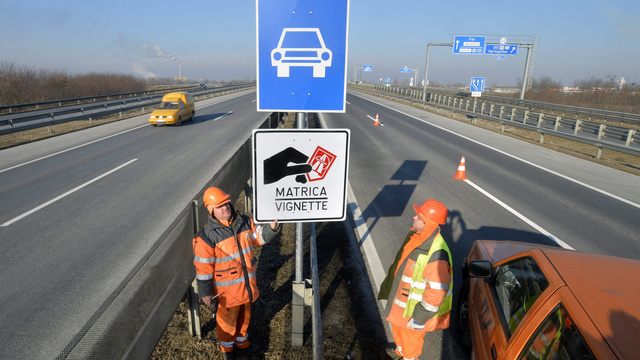 A Magyar Közút Nonprofit Zrt. munkatársai helyeznek ki egy, a fizetős autópálya-szakaszt jelző táblát az M0-áson december 31-én