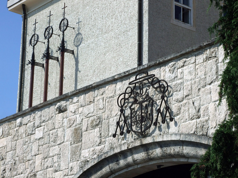 A Pannonhalmi Bencés Főapátság kovácsoltvasból készült címere a Szent Márton-hegyen a műemlék épületegyüttes főbejárata felett.