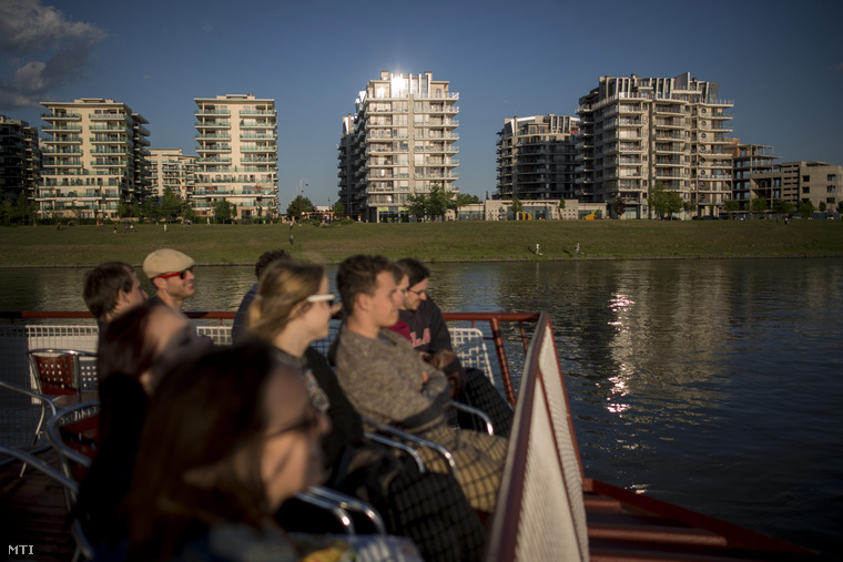 Turisták a BKK hajóján utaznak a Duna fővárosi szakaszán, háttérben a Marina Part lakópark házai 2015. május 11-én.