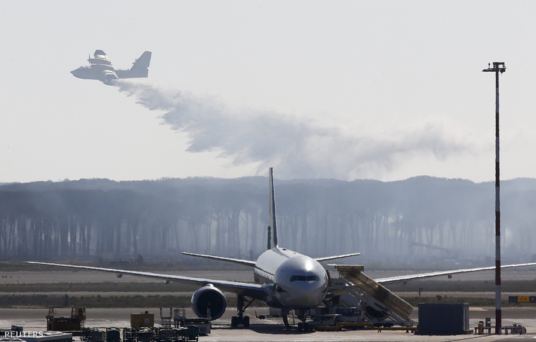 A Canadair tűzoltó repülőgépe oltja az erdőt a Fiumicino nemzetközi repülőtér közelében, Rómában.