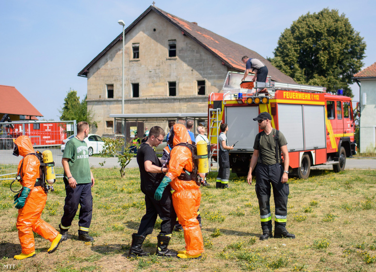 Védőöltözetet viselő tűzoltók a bajorországi Engelmannsreauthban 2015. augusztus 11-én, miután lezuhant egy amerikai F16-os harci repülőgép egy közeli erdős területen.