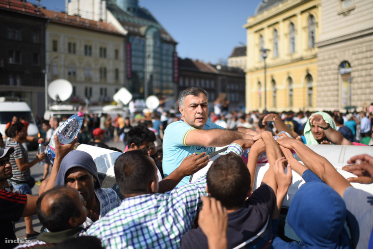 Ásványvizet osztanak a menekülteknek a pályaudvar főbejárata előtt.