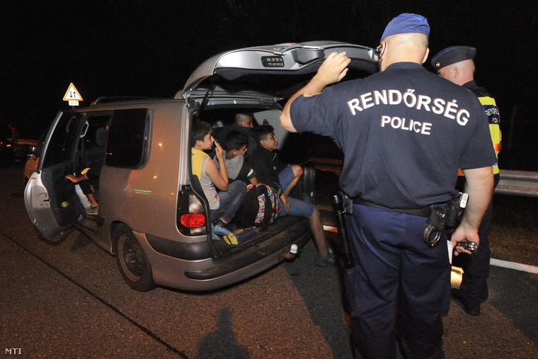 Egy rendőr felnyitja egy embercsempész határsértőkkel teli kocsijának csomagtartóját az M5-ös autópálya szatymazi pihenőjében 2015. szeptember 3-án.