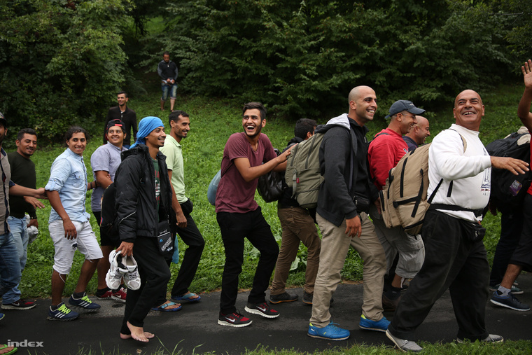 Városnéző busz turistáinak integetnek a menekültek a Gellért hegy oldalában