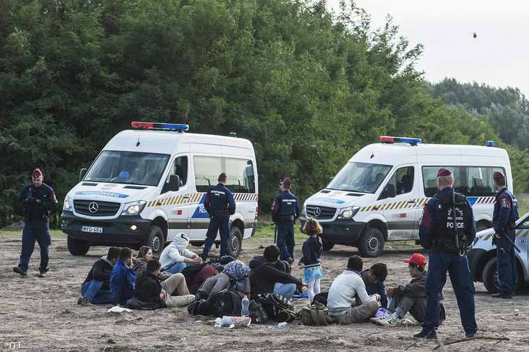 Rendőrök őrzik a megrongált műszaki határzáron átjutott menekülteket a röszkei átkelő közelében 2015. szeptember 15-én.